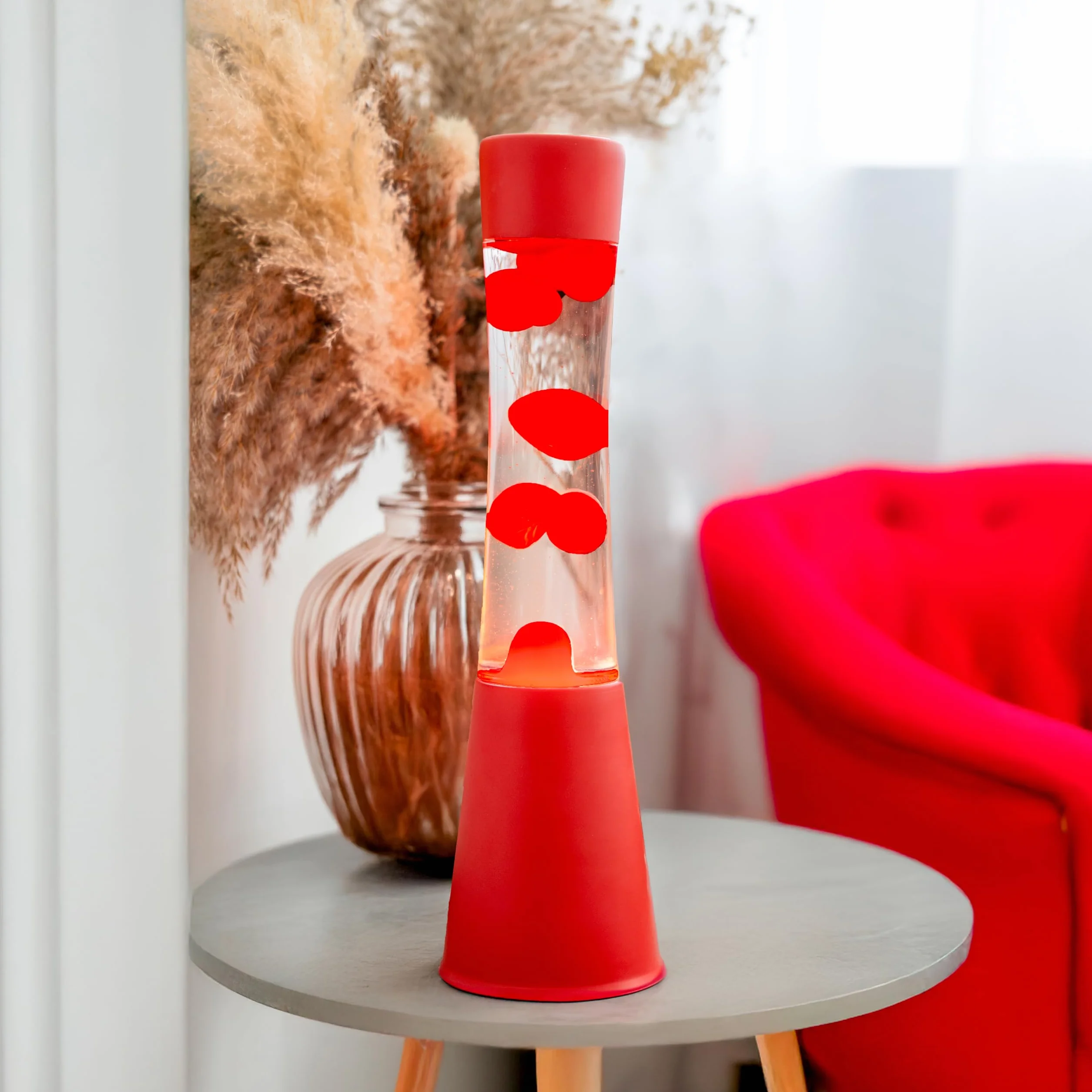 Fisura – Lampa z lawą czerwona. Podstawa i lawa w kolorze czerwonym z przezroczystym płynem. Lampa relaksacyjna z zapasową żarówką. 11 cm x 11 cm x 39,5 cm.